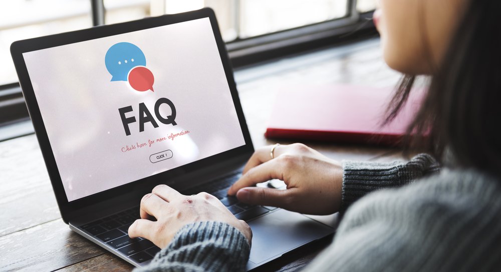 woman using a laptop with a FAQ text on the screen